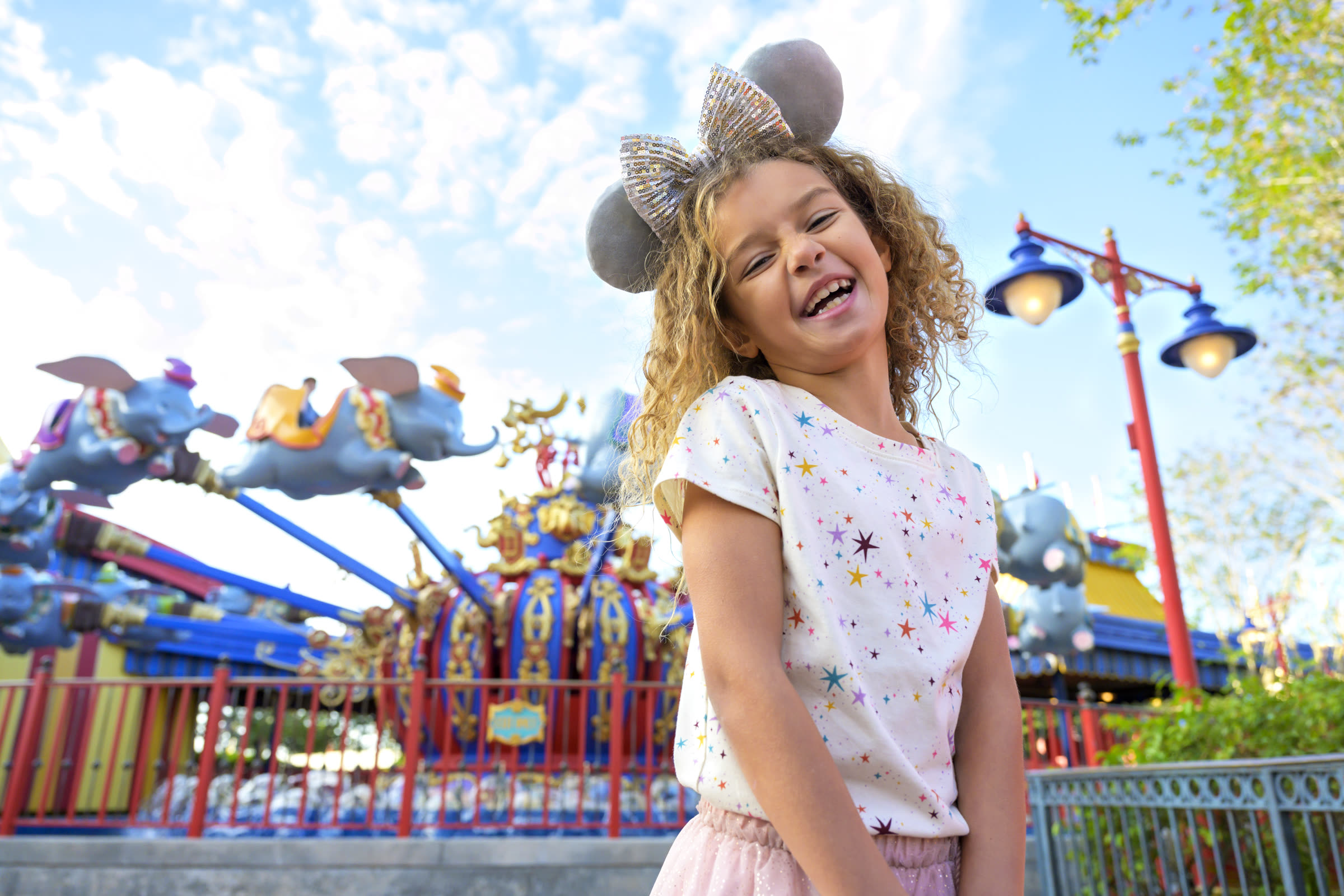 Young child smiling in Fantasyland with a spinning attraction behind